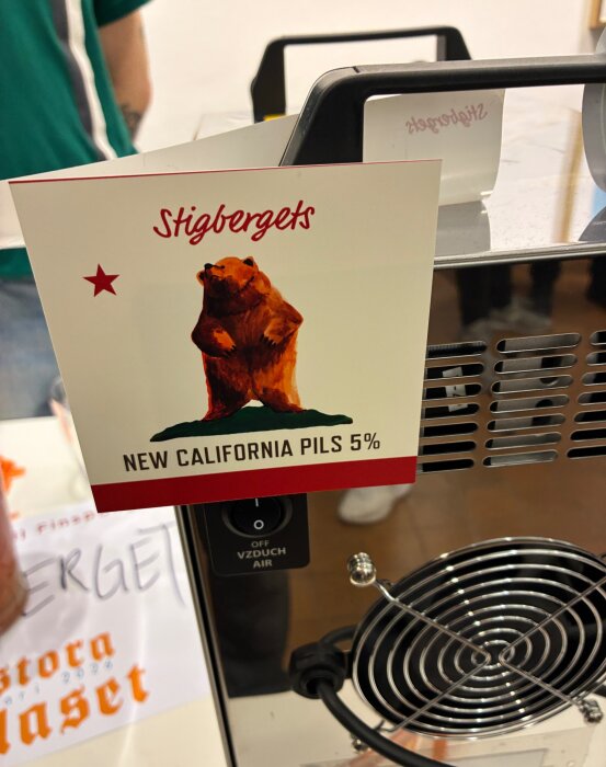 Öletikett från Stigbergets New California Pils 5% med en illustration av en björn.