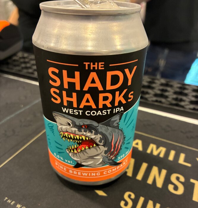 Burk med öl märkt "The Shady Sharks West Coast IPA" med en tecknad haj på etiketten.