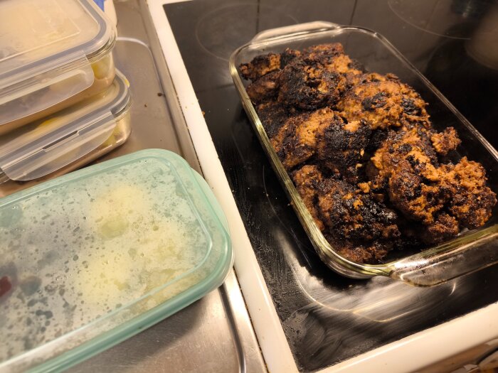 Matlådor med pannbiffar i glasform på spis bredvid en matlåda med tättslutande lock.