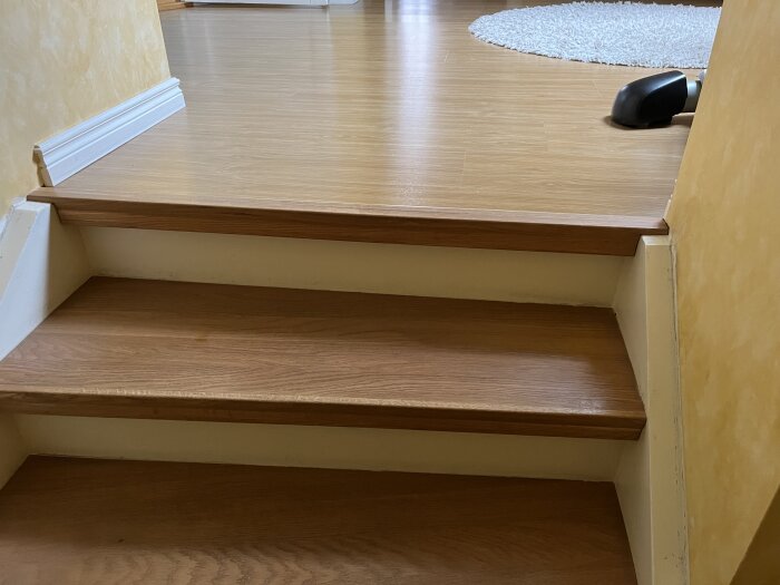 Wooden staircase with newly installed thin oak treads leading to a laminate floor, showcasing a home renovation project in progress.