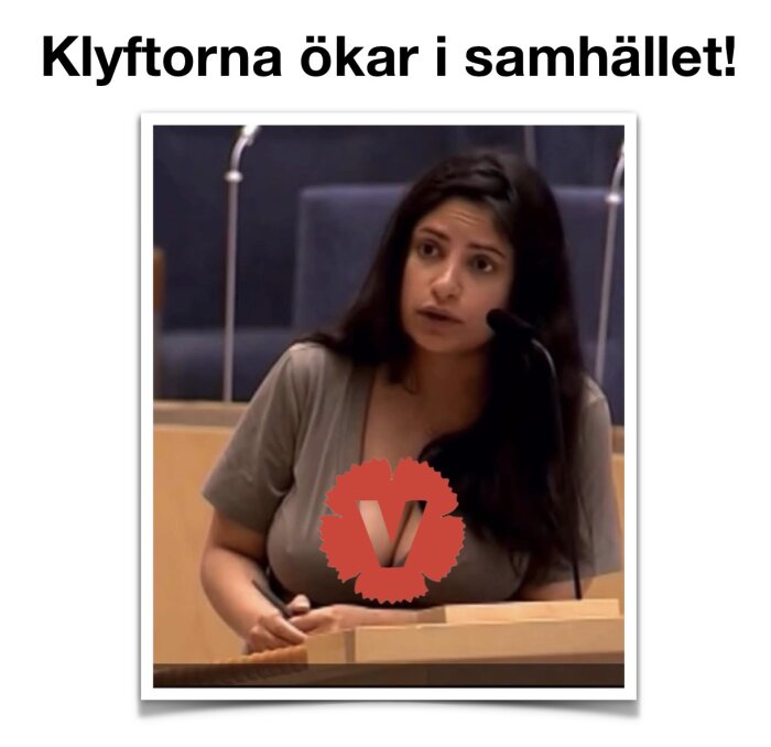 En person sitter vid ett podium och pratar i en mikrofon, med en röd logotyp med bokstaven "V" framför. Text ovan: "Klyftorna ökar i samhället!