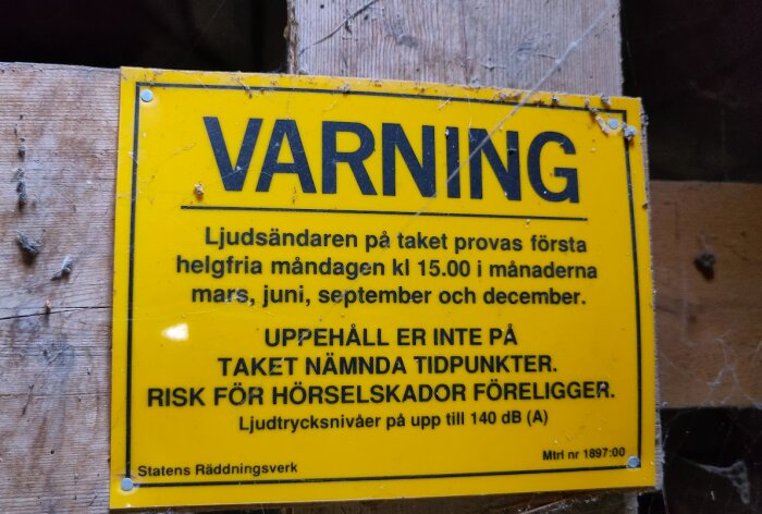 Gul varningsskylt med text om ljudsändare som testas måndagar kl 15 i mars, juni, september och december. Risk för hörselskador upp till 140 dB (A).