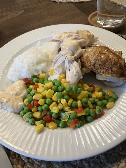 Matbild med grillad kyckling, ris, Àrtor, majs, paprika och mangochutneysÄs pÄ vit tallrik.
