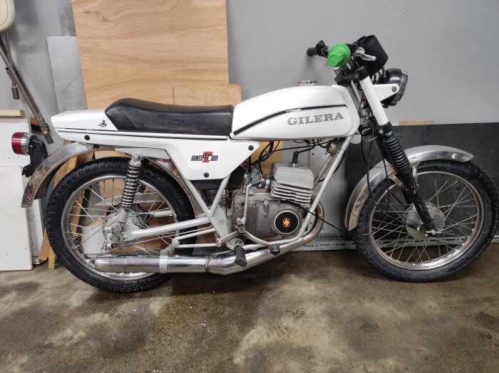Vit Gilera-moped parkerad i garage, nyligen inköpt efter tio år med tidigare moped.