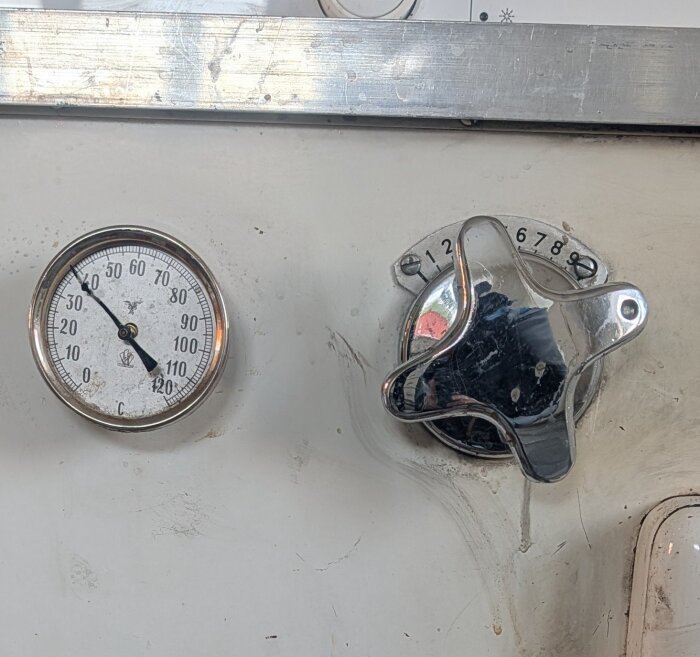 Termometer och ratt på pannans framsida för manuell justering av spjällen, med temperaturmätare från 0 till 120 grader.