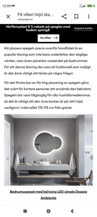 Rund spegel med LED-belysning ovanför ett handfat på ett stilrent badrum med grå väggar och dekorativa föremål.