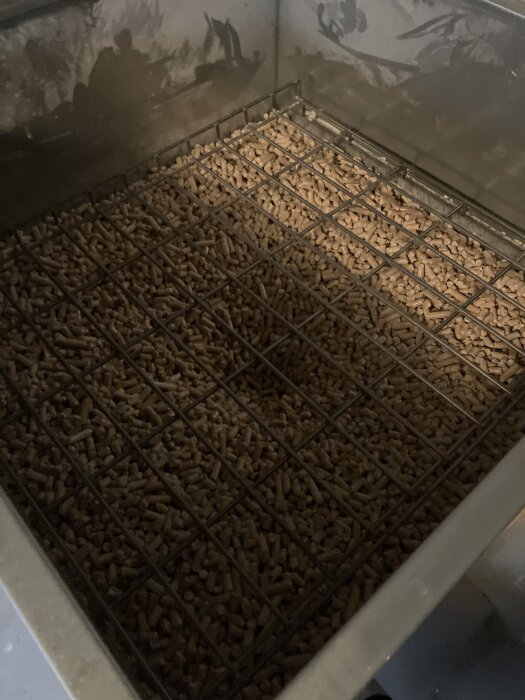 Pelletbehållare fylld med pellets med gallertäckning, del av diskussion om problem med CTC Ekoflex-anläggning.