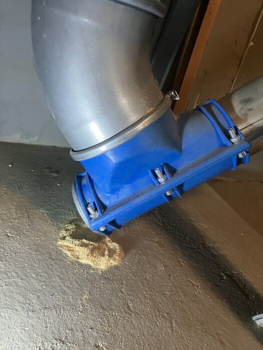 Grått och blått rörsystem där pellets ligger utspridda på golvet, potentiellt blockerar CTC Ekoflex-systemet.
