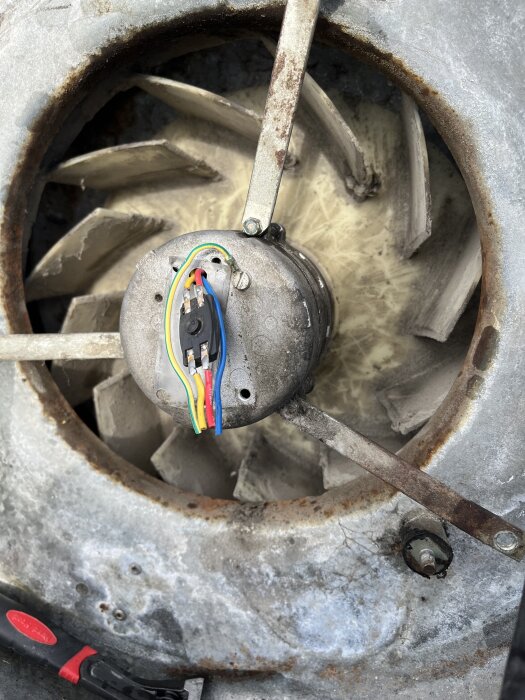 Färgglada kablar och en svart komponent syns på en motor, fråga om den svarta delens funktion i kabel-anslutningen till motorn.