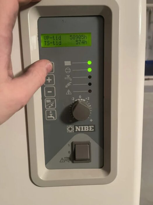 Nibe bergvärmepump kontrollpanel med vridknapp inställd på 5.5 av 9, blinkande blixtsymbol och en display som visar driftstid.