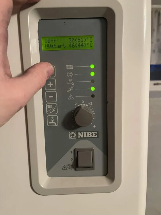 Kontrollpanel på Nibe bergvärmepump med display som visar temperaturinställningar; vridknapp och symboler synliga.