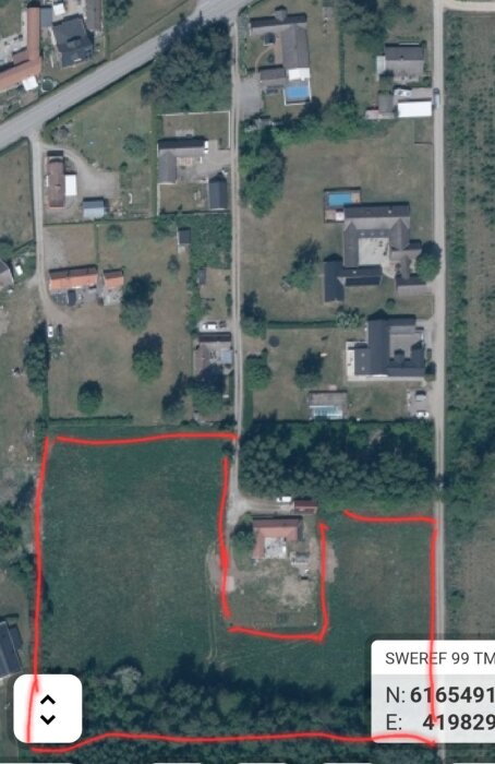 Flygbild över markområde omgiven av röda markeringar, potentiellt för byggprojekt, med hus och vägar i området.