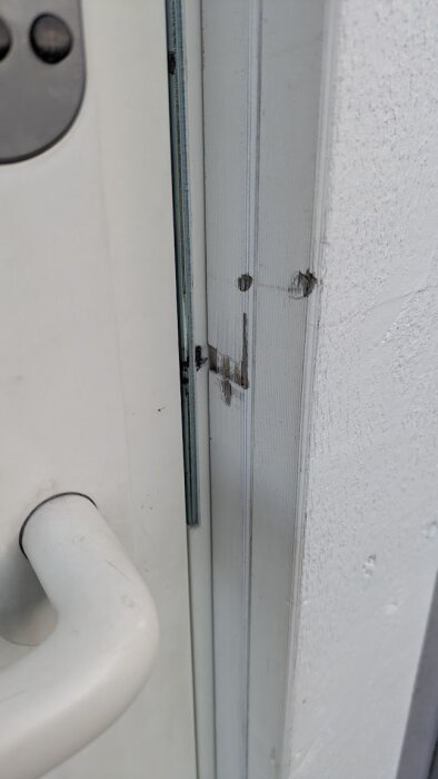 Ytterdörr och dörrkarm med märken där dörren tar emot; justeringsfråga relaterad till gångjärn.