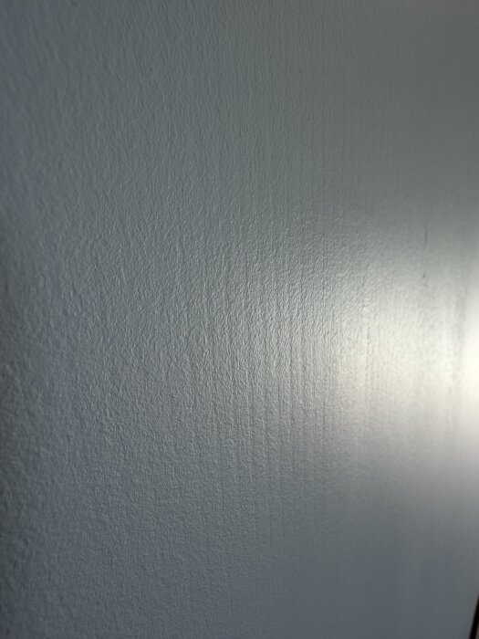 Närbild av en vägg med nyligen målad yta som visar svaga lodräta ränder i färgen.