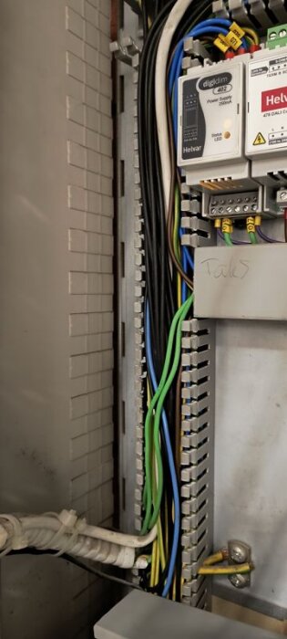 Elcentral med olika kablar och komponenter, inklusive enhet märkt "Helvar". Kablar är organiserade i centralen och olika säkringsfabrikat syns.