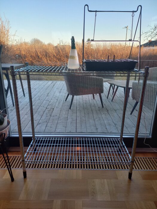 Gallerhylla från IKEA med sprayflaska och odlingslåda med plantor, placerad vid ett fönster med utsikt över en altan.