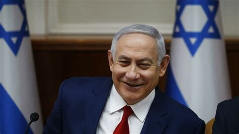 Jag vet inte vem personen på bilden är, men det är en man i kostym med två israeliska flaggor i bakgrunden.