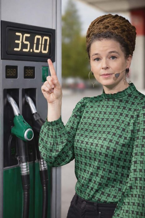 Kvinna pekar på bensinprisdisplay som visar 35,00 vid en bensinpump.