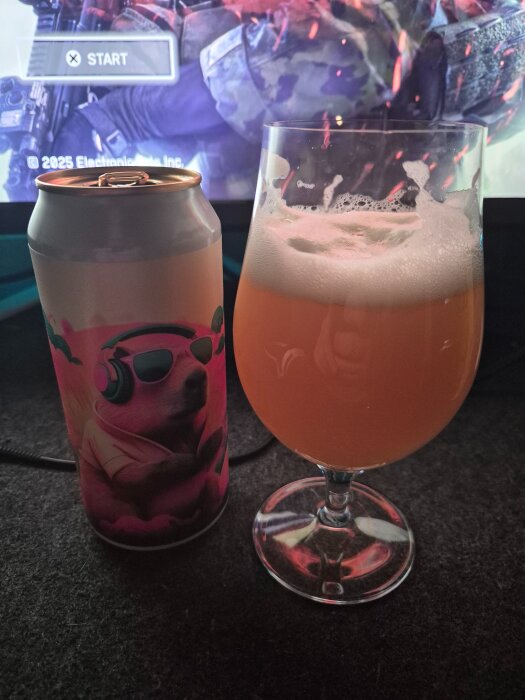 En burk med färgglad design och ett glas öl framför en datorskärm med spelstart-menyn.