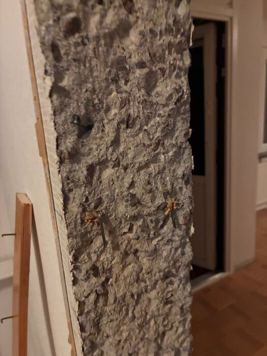 Närbild av ojämn, bilad betongväggsöppning med utskjutande spikar.