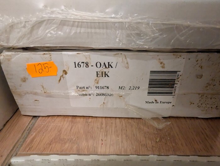 Paket med 3-stavs ekparkett, märkt "1678 - Oak/Eik", 2,219 m², pris 125 kr. Plastförpackning med etikett och streckkod, smutsig kartong.