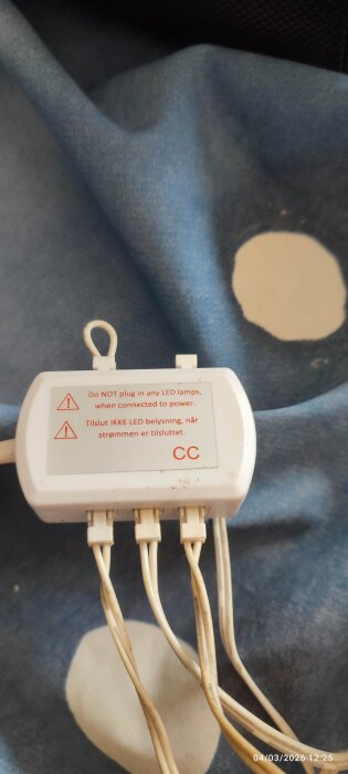 Vit kopplingsdosa med varningstext om att inte ansluta LED-lampor under ström. Kablar är anslutna till dosan.
