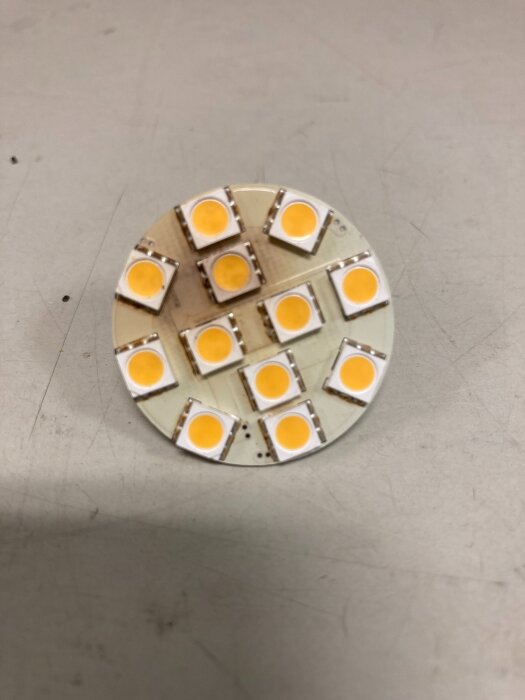 Rund kretskort med flera ytmonterade lysdioder (LEDs) på en ljus bakgrund.