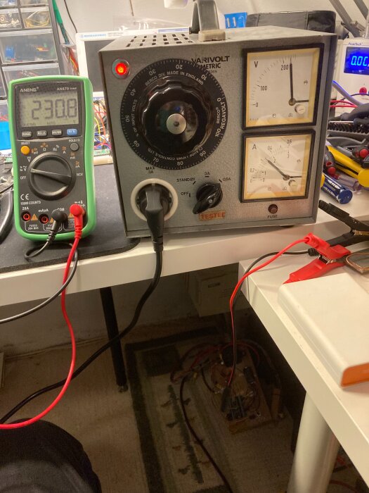 Multimeter vid 230V, variabel transformator med mätare för volt och ampere, kablar anslutna på ett arbetsbord.
