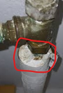 Rörisolering med misstänkt gammal mineralull, möjligtvis stenull, markerad med röd cirkel nära ett metallfäste.