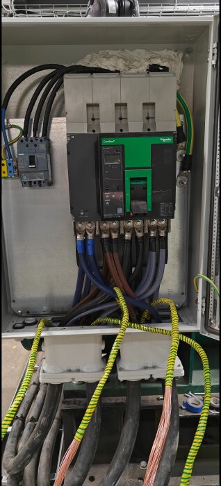 Elcentral med flera kopplade kablar, gröna och svarta, i en strömbrytare. Installationen visar en parallellkoppling med ansluten fläns.
