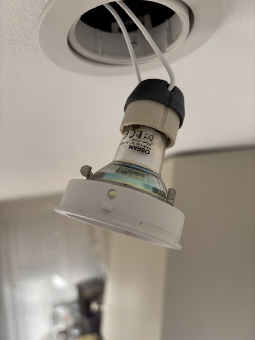 Dimbar LED GU10 spotlight som är delvis urtagen från taket, med synliga ledningar, och har en bränd, svart yta inuti glaset.