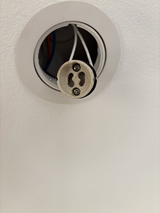 Utbränd takspotlight med exponerad sockel och kablar, möjligt elektriskt fel med smältskada inuti en dimbar LED GU10-lampa.