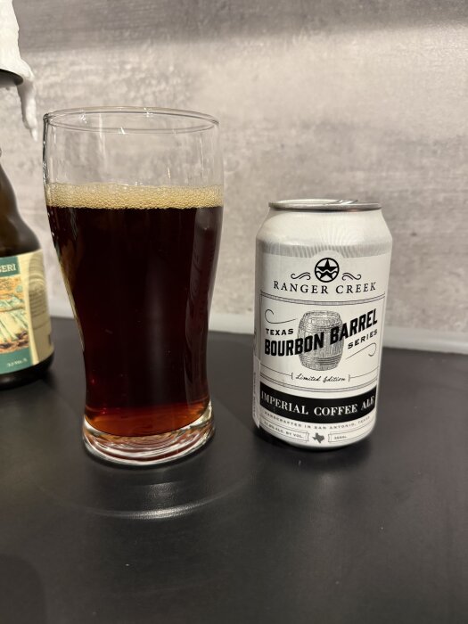 Ett glas mörk öl och en burk märkt "Ranger Creek Texas Bourbon Barrel Imperial Coffee Ale" på ett bord.