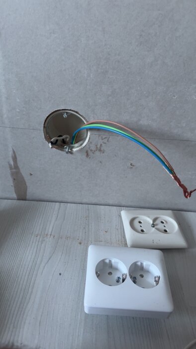 Elektriska kablar dras om i vägg bakom gips i barnrum, med två dubbla eluttag i förgrunden på golvet.
