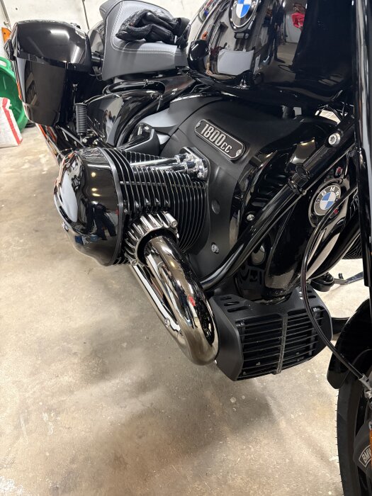 Svart motorcykel med 1800cc-motor parkerad i ett garage, visar motor och avgassystem, del av BMW-logotypen synlig.