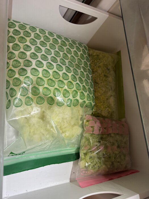 Fryslåda innehållande plastpåsar med fryst hackad lök och selleri.