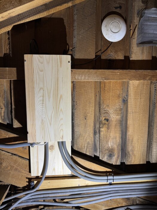Hemmagjort nätverksrack av en 10” panel och hyllplan, med slangar fästade med klickfästen. Tak i trä och elektrisk utrustning syns.