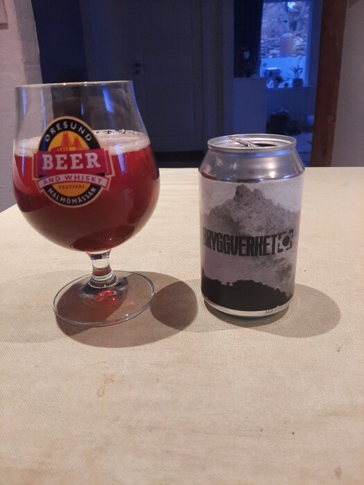 Glas med rödbrun öl och en ölburk märkt "Bryggverket" på ett bord.