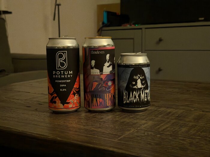 Tre ölburkar med olika etiketter står på ett träbord. Från vänster: Potum Brewery Powertrip, Elm Eleven Othervoice, Black Metal.