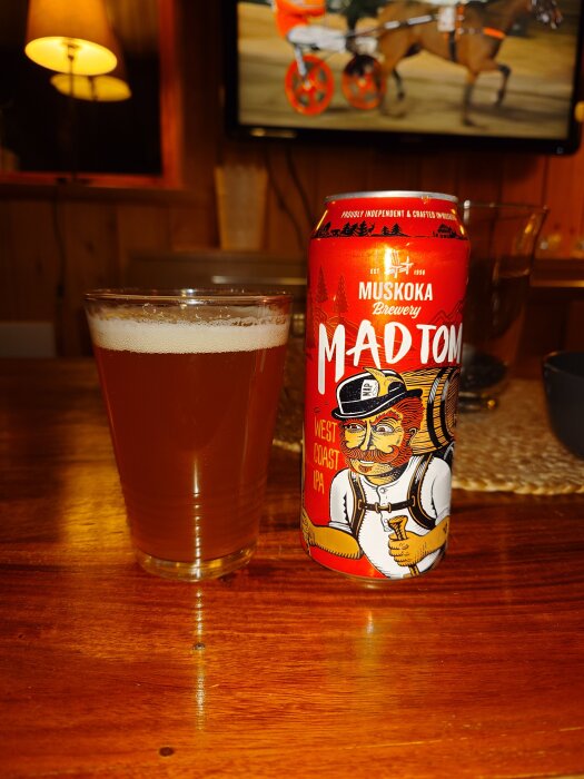 En burk Mad Tom West Coast IPA från Muskoka Brewery bredvid ett glas öl på ett träbord.