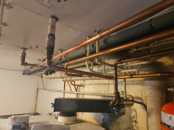 Rörsystem i källare med kopparrör och ventiler kopplat till IVT Greenline värmepump.