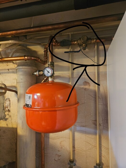 Rörsystem med ett rött expansionskärl och en markerad plats där ett filter sitter monterat i ett kopparrör.