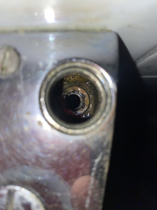 Närbild av ett insexnyckelhål på en Mora Ess duschblandare, omgiven av metall och tecken på rost.