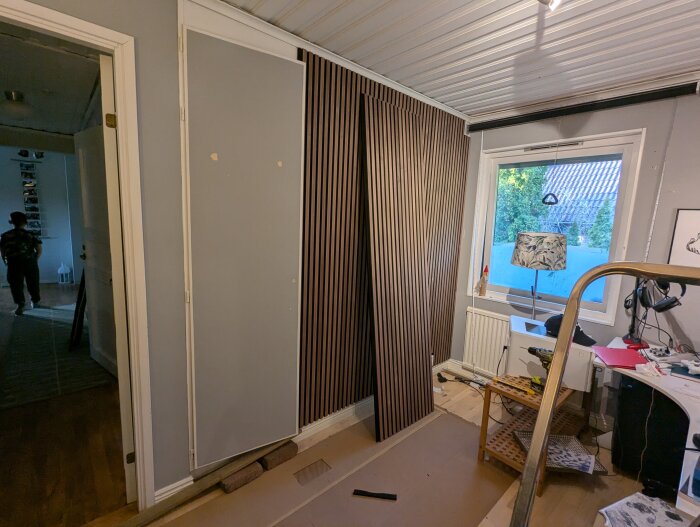 Garderobsdörr och paneler mot en vägg i ett rum, där panelen står lutad mot väggen och dörren är utan dekoration.