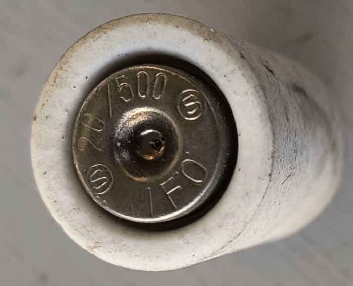 Gammal porslinssäkring, D2 propp med mässingsdetaljer, märkt "20/500" och "IFÖ". Visar variation i design och utförande.