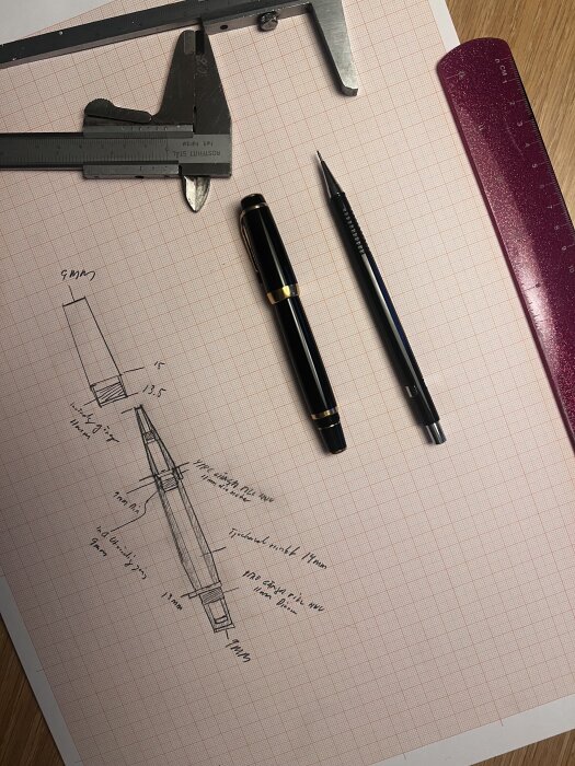 Ritning på milimeterpapper med penna, stållinjal och skjutmått för ett planerat svarvprojekt i mässing.