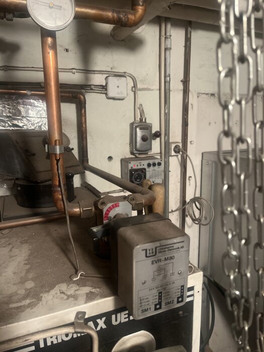 Kedjor och rörsystem med mätinstrument och elektrisk enhet i en industriell miljö.