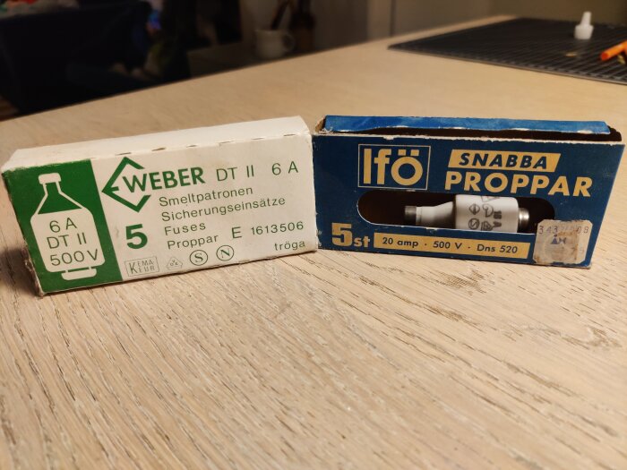 Två kartonger på ett bord, en vit med "Weber 6A" säkringar och en blå med "Ifö" snabba proppar, båda 500V märkta.