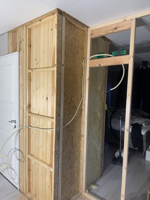 Väggkonstruktion med träpanel och elkablar förbereds för belysning i framtida garderober, sett i en oinredd byggnadsdel.