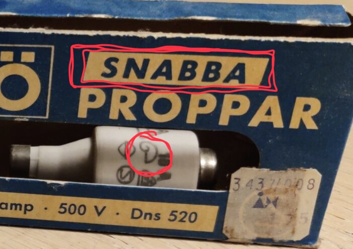 Snabbsäkringar i en blå och gul kartong, varav en säkring är markerad med handskrivna symboler.